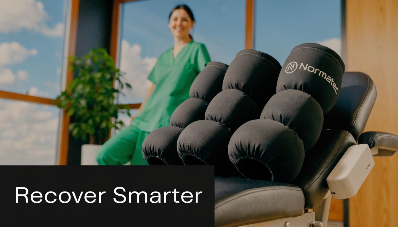 A healthcare professional standing beside a Normatec compression recovery system displayed in a modern clinical setting.