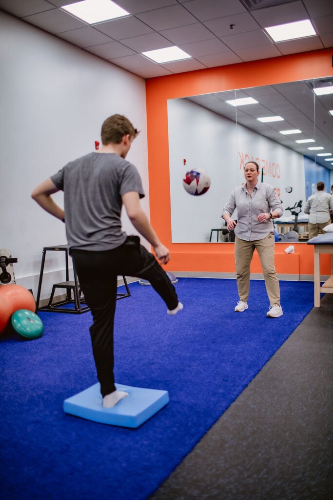 physical therapist working with an athlete with soccer ball